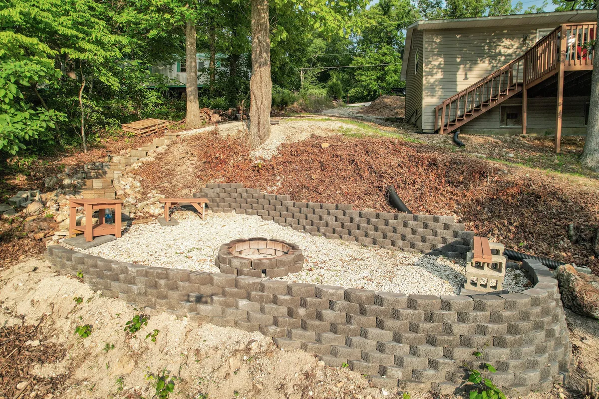 A cozy outdoor fire pit surrounded by comfortable seating and encircled by tall trees. The setting is ideal for evening gatherings, storytelling, and enjoying the natural surroundings under the stars.