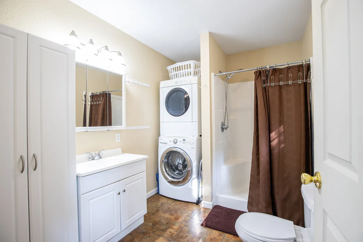 This interior photo highlights practical amenities including a washer and dryer, a shower area, and a vanity with a mirror. The setup is clean and convenient, underscoring the ease of keeping swimsuits and towels fresh for daily lake adventures.