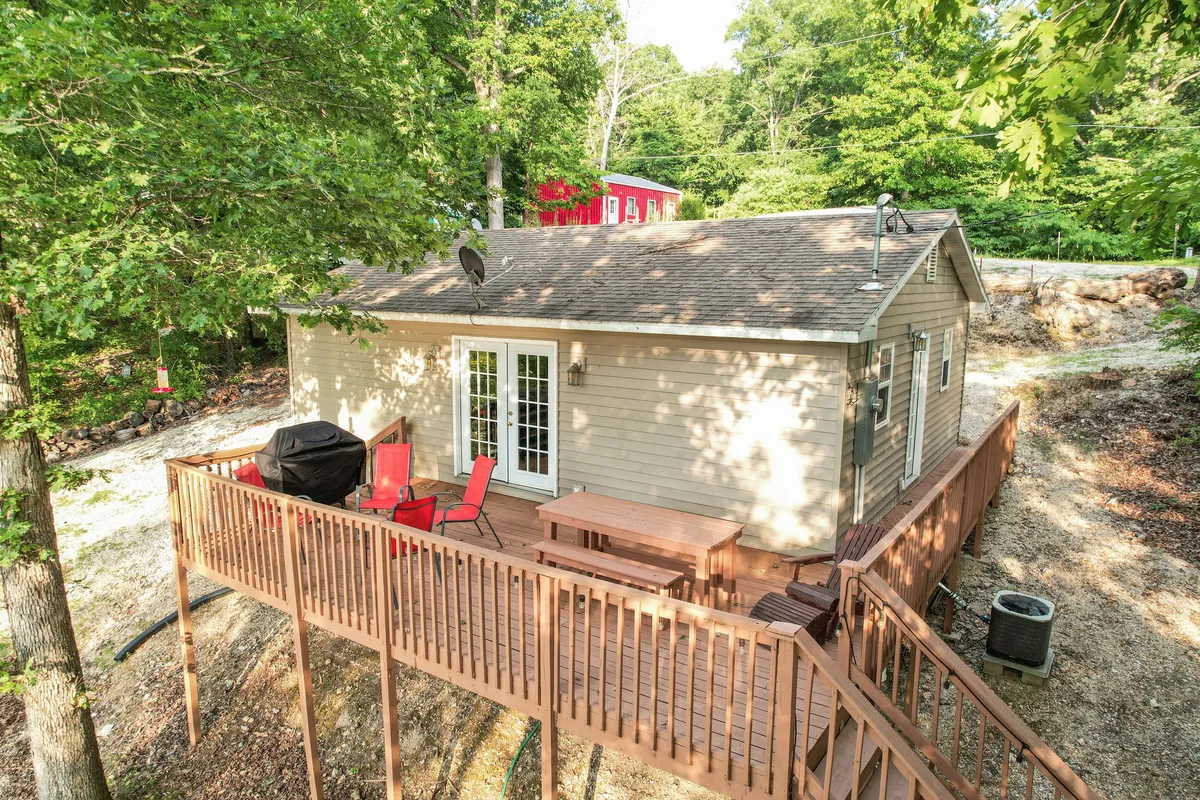A welcoming lakeside deck furnished with red chairs and an outdoor grill, overlooking the water. The setting is perfect for sunset relaxation after a day of exploring nearby towns or enjoying the local nightlife.