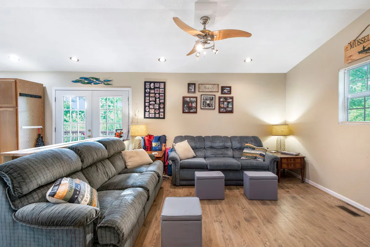 A cozy living room with plush sofas arranged for conversation and movie nights. The family photo wall and soft lighting create a welcoming, homey atmosphere designed for relaxation and connection. The overall mood is inviting, perfect for quiet mornings or lively evenings.