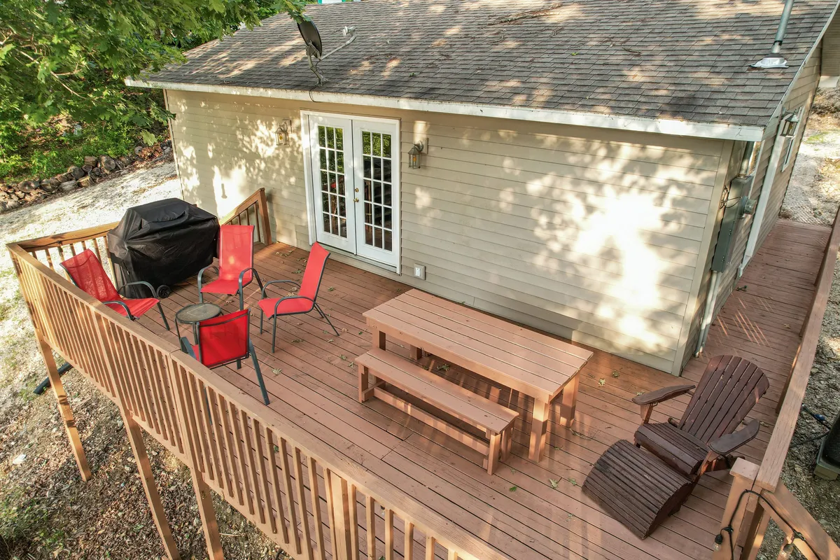 This image shows an inviting exterior deck area furnished with comfortable seating and a grill, framed by double doors that hint at easy indoor-outdoor flow. The space is ready for outdoor dining, barbecues, or simply relaxing after a day of adventure.