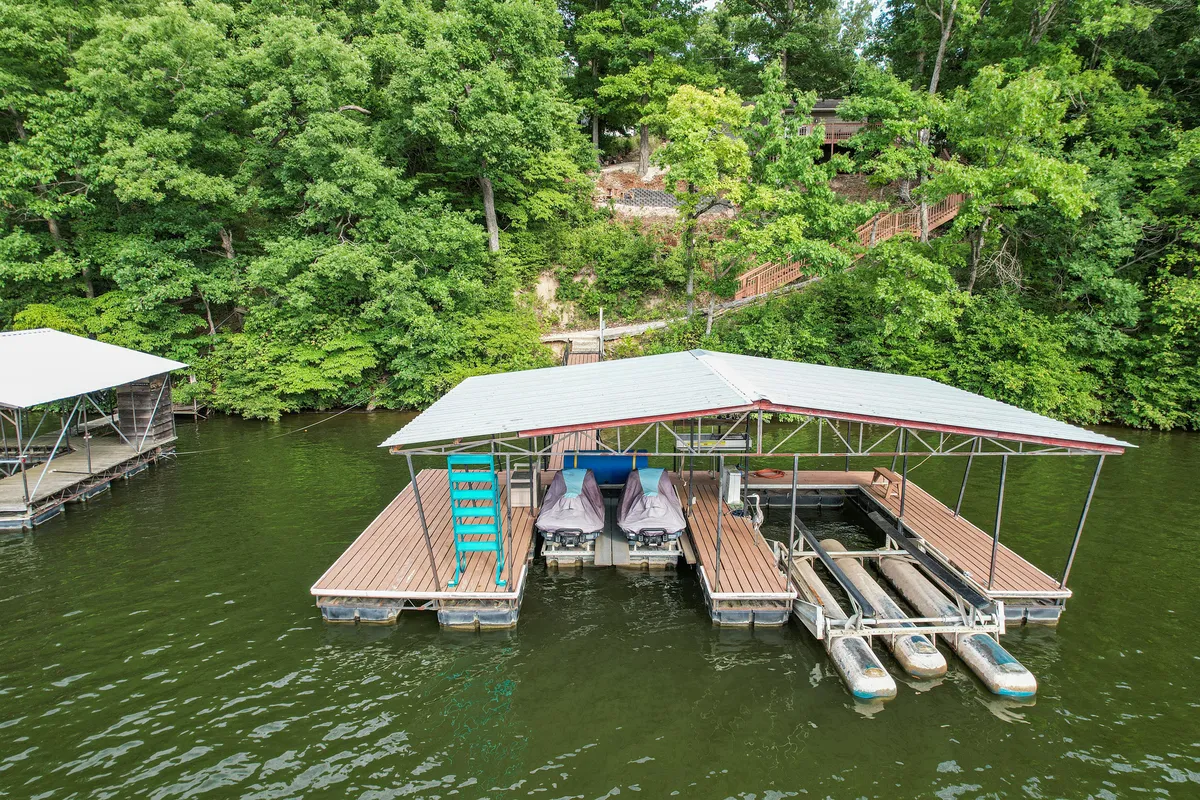 A peaceful dock stretches out over calm water, with boats moored and verdant greenery along the shore. The scene invites thoughts of family fishing trips, boating excursions, and lakeside relaxation.