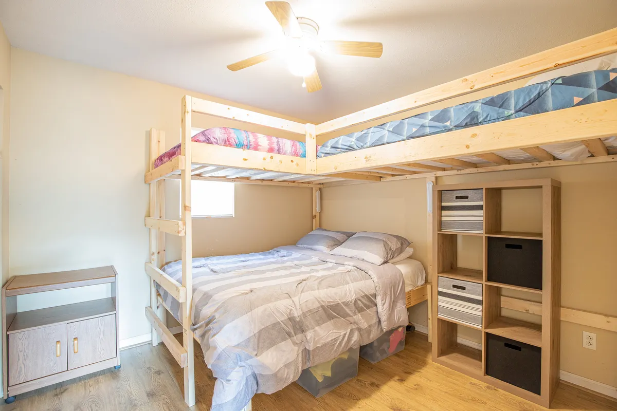 A compact nook featuring a twin bunk bed and shelving, styled with family-friendly decor and a bedside table. The setup highlights efficient use of space for children or additional guests, making it ideal for sleepovers or family stays.
